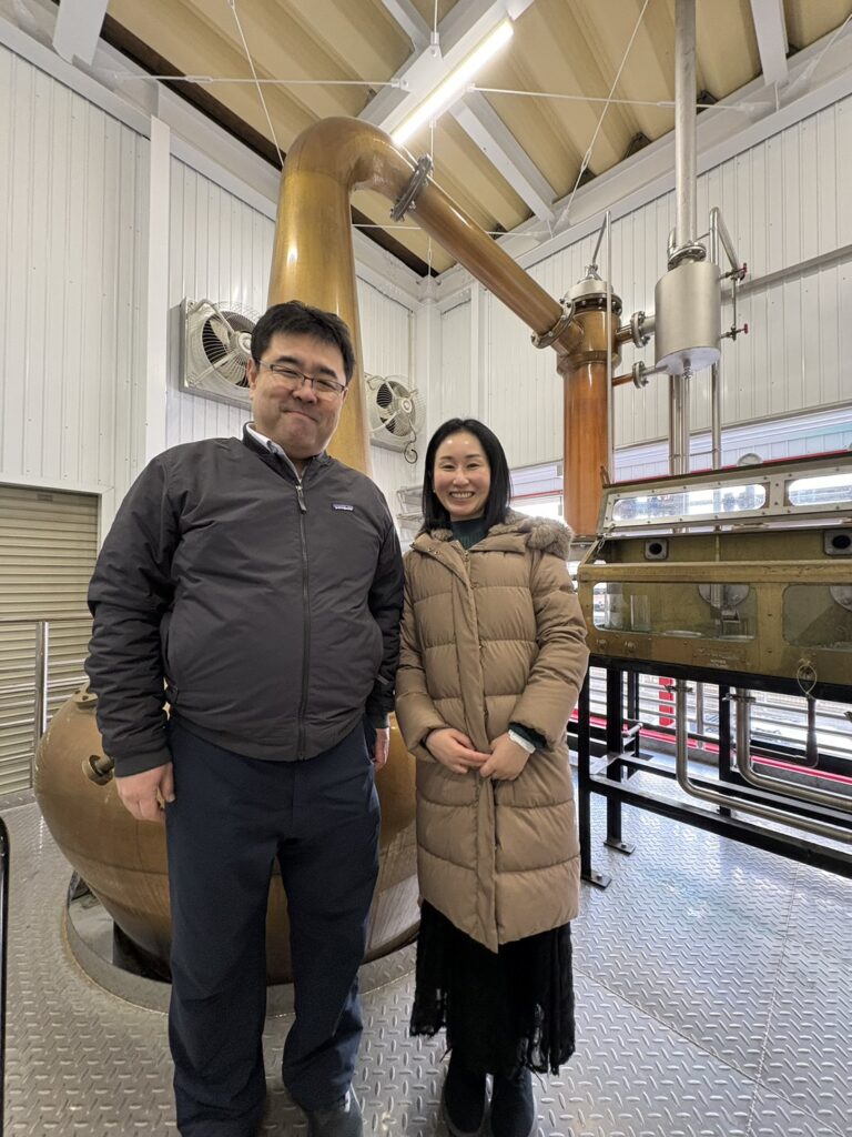 A moment of 'Hitsuzen' (Inevitability) at Kameda Distillery: Mika Tanimoto and President Tokida standing before the copper pot stills that craft Niigata's most 'beautiful' whisky