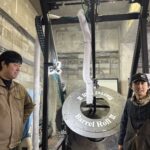 President Takahiko Inagaki of Saburomaru Distillery with a cooper and his invention, 'Barrel Roll 2,' showcasing the heart of Japanese whisky innovation to Mika Tanimoto.